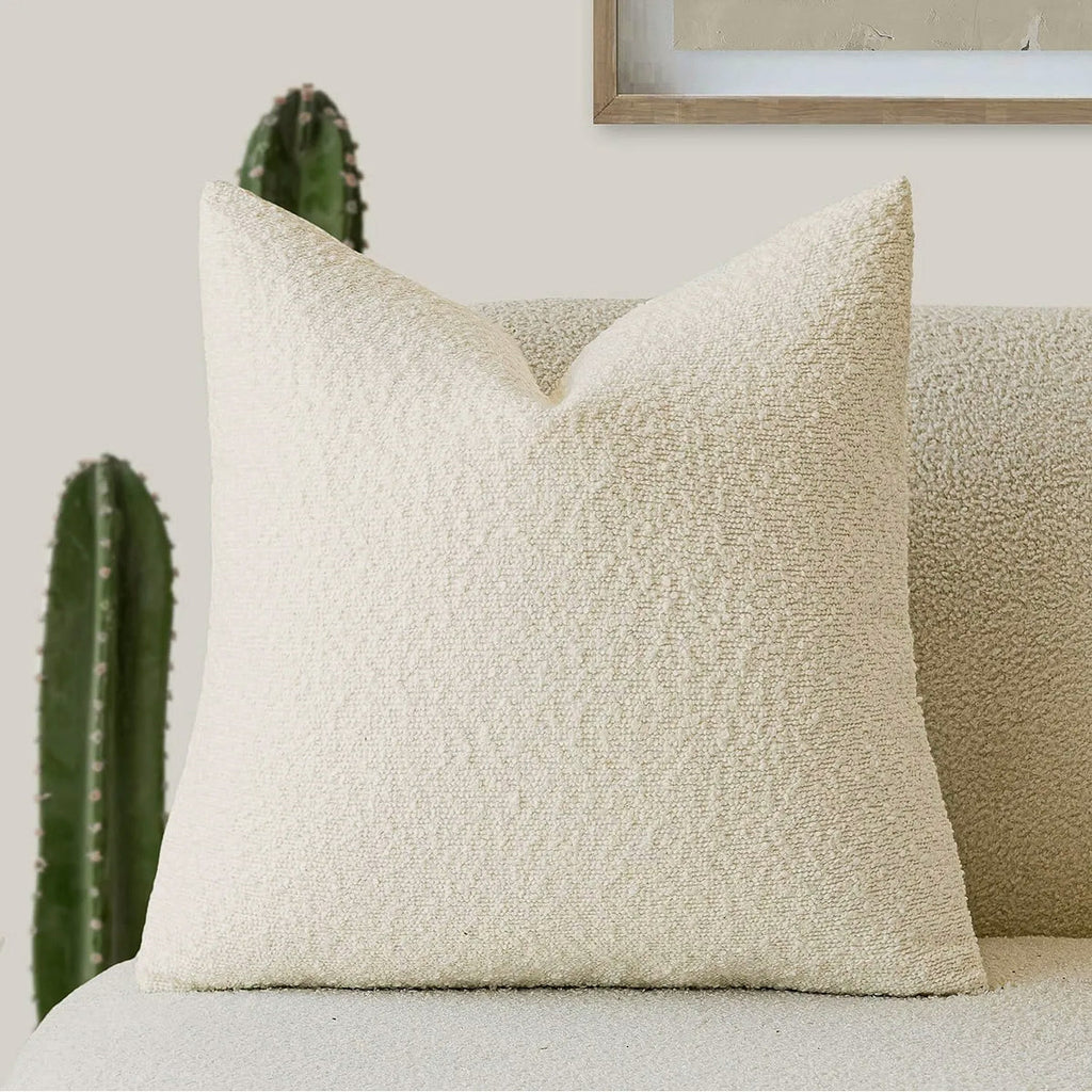 Housse de coussin bouclette crème vue de près sur un canapé, boucles serrées bien visibles