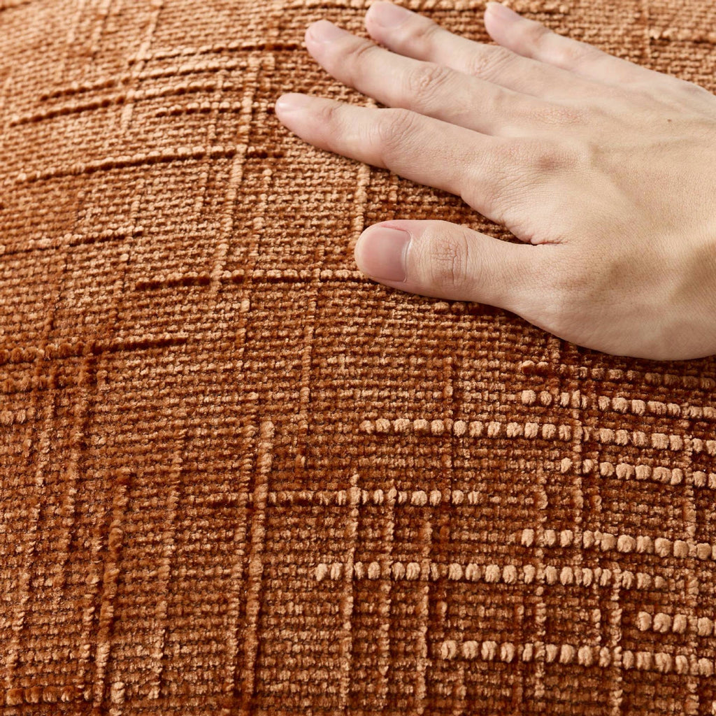 Main posée sur une housse de coussin en chenille mandarine, relief du tissage en gros plan