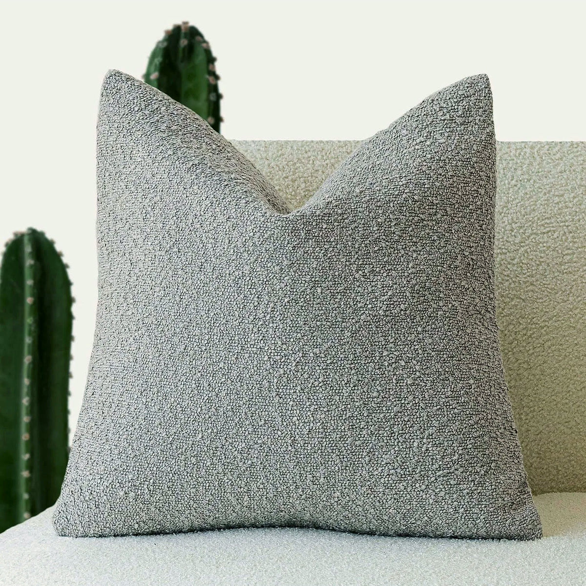 Housse de coussin bouclette gris clair de face sur un canapé
