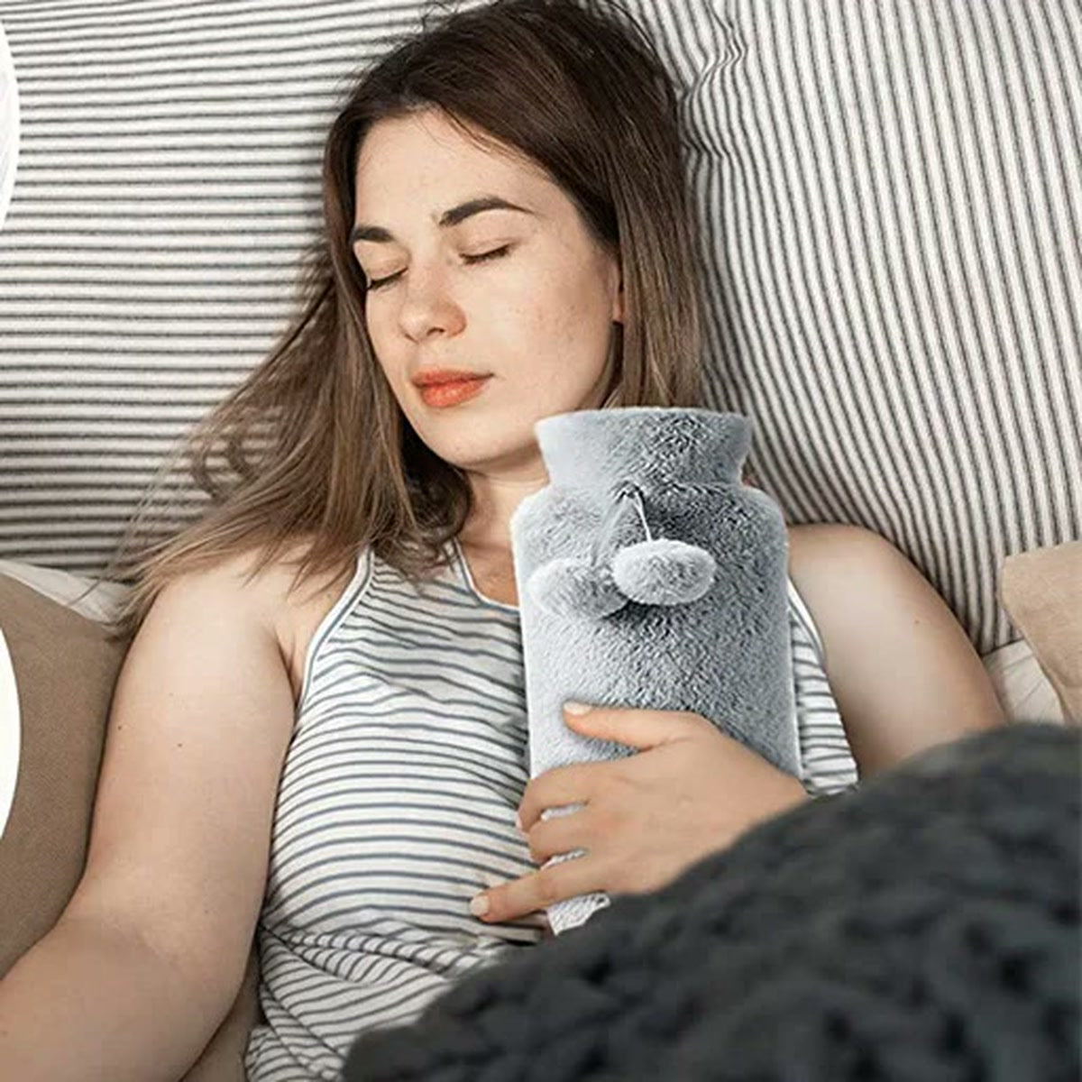Femme qui se repose avec la bouillotte longue grise contre elle