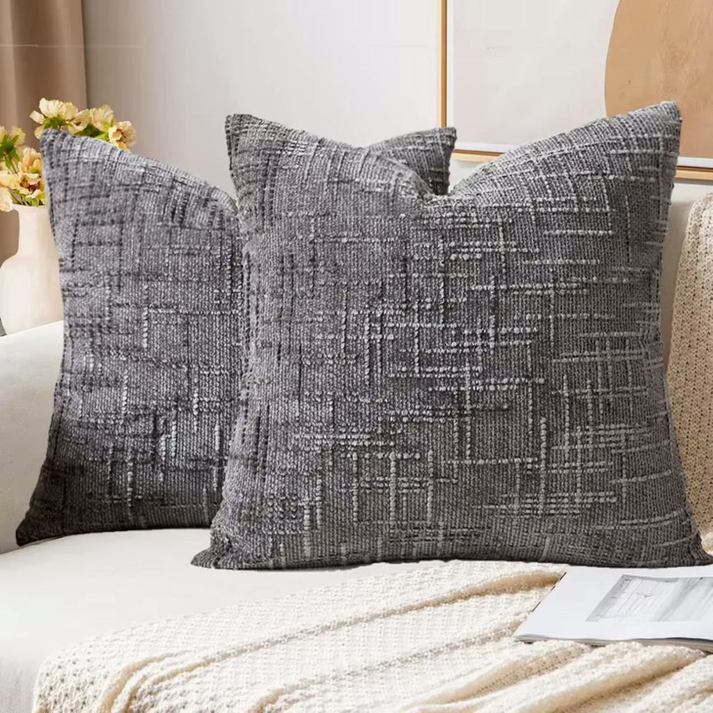 Deux housses de coussin en chenille gris foncé sur un canapé clair