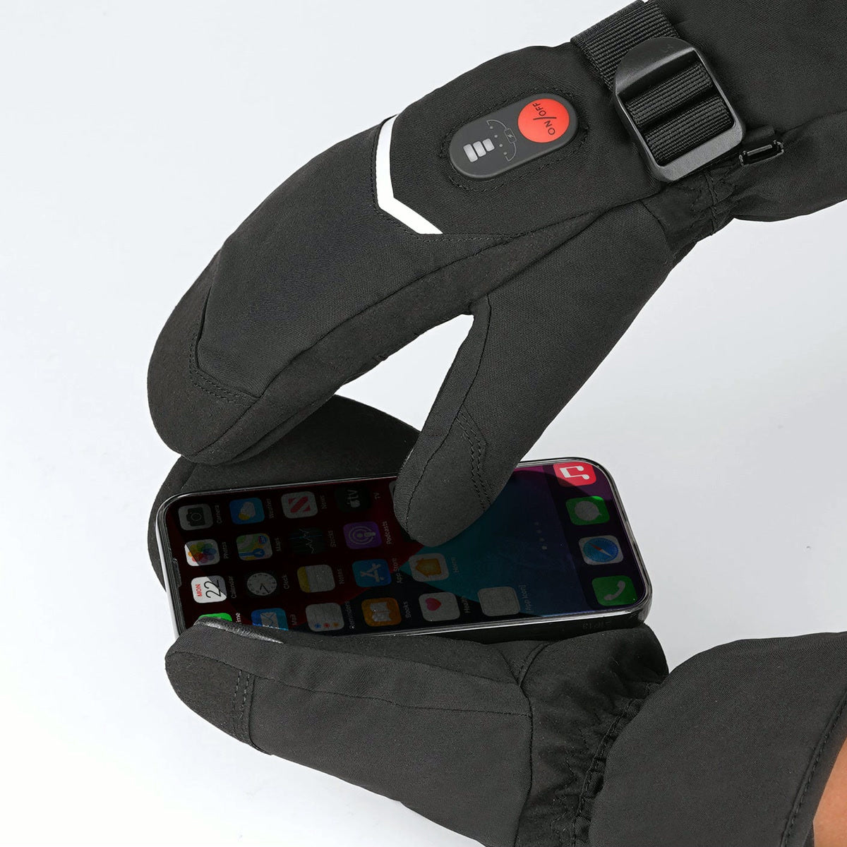 Moufle chauffante portée, l’index séparé posé sur l’écran d’un téléphone, bouton de réglage sur le dos